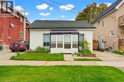 White siding exterior with a dark shingle roof, featuring an enclosed front porch with multiple windows - 