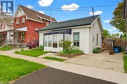 White siding exterior with a dark shingle roof and an awning over the front window - 