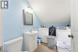 Full bathroom featuring a white vanity with integrated sink, a toilet, and a wall-mounted vanity light - 