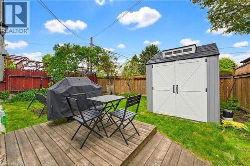 Expansive rear yard featuring a wood deck, manicured lawn, and a modern storage shed with barn-style doors - 291 Park Avenue, Brantford, ON - Outdoor With Deck Patio Veranda