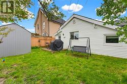 Expansive green lawn with a wooden storage shed, a ground-level deck, and a wood lattice fence - 