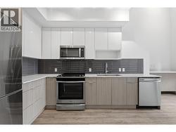 Gourmet kitchen featuring quartz countertops, sleek cabinetry, and stainless steel appliances. - 