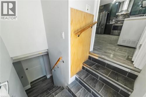 Staircase featuring dark tile steps with contrasting risers and a wood handrail - 158 Plymouth Road, Kitchener, ON - Indoor Photo Showing Other Room
