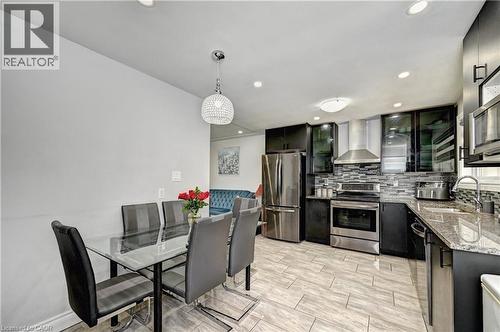 Modern kitchen featuring stainless steel appliances, dark cabinetry, and granite countertops - 158 Plymouth Road, Kitchener, ON 