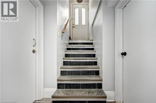 Staircase featuring dark square tile risers and light-toned tile treads with protective edging - 158 Plymouth Road, Kitchener, ON 