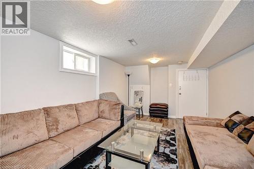 Spacious room featuring wood-finish flooring, a white-framed window, and a textured ceiling - 158 Plymouth Road, Kitchener, ON 