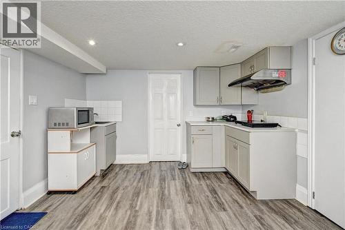 Kitchenette featuring wood-finish flooring, white walls, and light gray cabinetry - 158 Plymouth Road, Kitchener, ON 