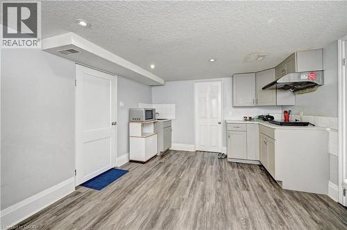 Functional kitchen space featuring grey cabinetry, wood-finish flooring, recessed lighting, and white baseboards - 158 Plymouth Road, Kitchener, ON 