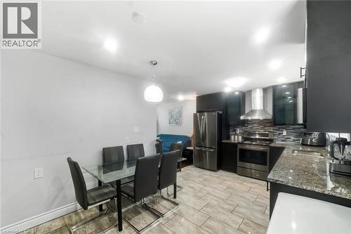 Open-concept kitchen featuring stainless steel appliances, dark cabinetry, and a stone-finish countertop - 158 Plymouth Road, Kitchener, ON - Indoor