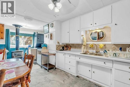 Kitchen featuring white cabinetry, a double basin sink, and a stacked washer and dryer - 1264 Parkinson Road, Woodstock, ON 