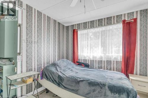 Room featuring striped wallpaper, a large window with sheer and red drapes, and a ceiling fan - 1264 Parkinson Road, Woodstock, ON 