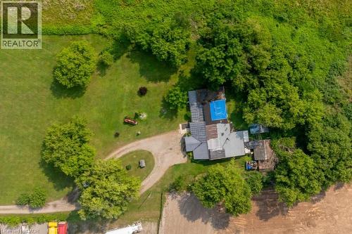 Aerial property overview featuring a circular gravel driveway, extensive green lawn areas, established trees, and a rectangular blue-covered structure - 1264 Parkinson Road, Woodstock, ON 