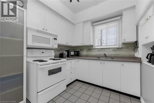 Kitchen featuring white cabinetry, a built-in microwave, an electric range, a stainless steel sink, and a tiled backsplash - 205 Ferguson Avenue S, Hamilton, ON - Indoor Photo Showing Kitchen