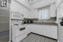 Kitchen featuring white cabinetry, a built-in microwave, an electric range, a stainless steel sink, and a tiled backsplash - 