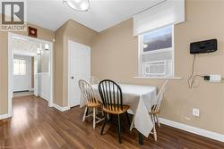 Dining area featuring wood-finish flooring, a window with an integrated air conditioning unit, and a flush mount ceiling light fixture - 
