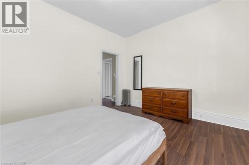 Room featuring wood-finish flooring, white baseboards, and a doorway with a folding door - 205 Ferguson Avenue S, Hamilton, ON - Indoor Photo Showing Bedroom