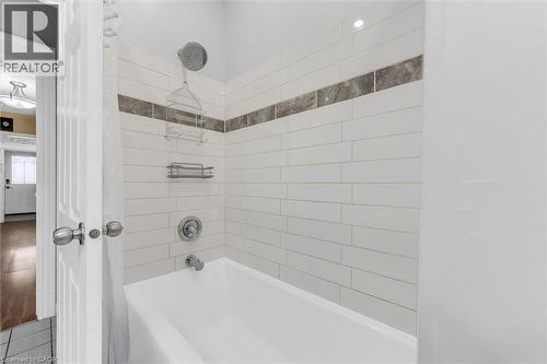 Bathtub with subway tile surround, featuring a decorative mosaic accent band - 205 Ferguson Avenue S, Hamilton, ON - Indoor Photo Showing Bathroom