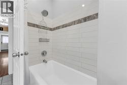 Bathtub with subway tile surround, featuring a decorative mosaic accent band - 