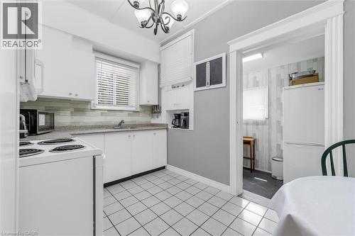 Well-appointed kitchen featuring white cabinetry, a light-toned backsplash, and a window above the sink - 205 Ferguson Avenue S, Hamilton, ON - Indoor Photo Showing Kitchen