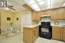 Kitchen featuring light wood cabinetry, light countertops, a black electric range, and a full ceiling light panel - 
