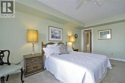 Carpeted bedroom featuring light green walls, a white ceiling fan, and a wood-finish headboard - 