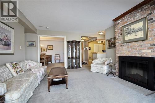 Brick-front fireplace with a black surround, framed by a wood mantel - 237 King Street W Unit# 1305, Cambridge, ON - Indoor Photo Showing Living Room With Fireplace