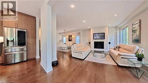 Open concept living space featuring wood-finish flooring throughout, recessed lighting, and a modern fireplace with a wall-mounted display - 63 Ian Ormston Drive, Kitchener, ON - Indoor Photo Showing Living Room With Fireplace