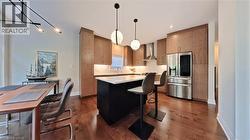 Contemporary kitchen featuring a dark-toned island with a light-toned countertop, wood-finish cabinetry, and stainless steel appliances - 