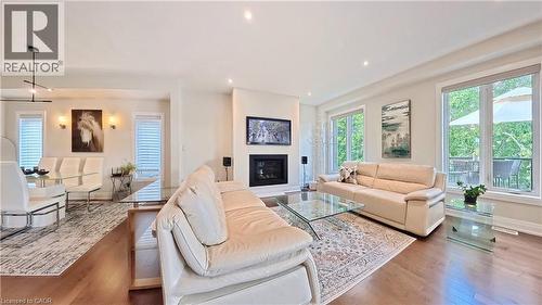Open-concept living area featuring rich wood-finish flooring, a contemporary fireplace with a mounted television, and recessed ceiling lighting - 63 Ian Ormston Drive, Kitchener, ON - Indoor Photo Showing Living Room With Fireplace