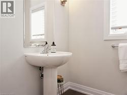 Pedestal sink with chrome faucet, featuring an overhead mirror and sconce lighting - 