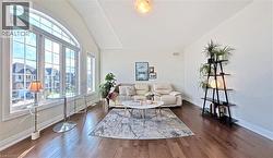 Spacious living area featuring expansive arched windows, vaulted ceilings, wood-finish flooring, and light-toned walls - 