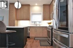 Contemporary kitchen featuring a dark-toned island with a light countertop, wood-finish flooring, and natural wood cabinetry - 