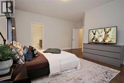 Spacious room featuring wood-finish flooring, light neutral wall paint, and a door opening to an adjacent bathroom - 