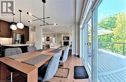 Open-concept living space with wood-finish flooring, a contemporary dining area, and a kitchen featuring dark wood cabinetry and stainless steel appliances - 