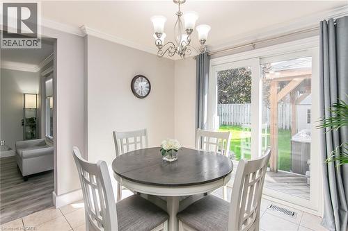 Dining area with tiled flooring and a chandelier, featuring crown molding, a sliding glass door to the exterior, and a backyard with a grass lawn and wood decking - 529 Chesapeake Crescent, Waterloo, ON - Indoor Photo Showing Dining Room