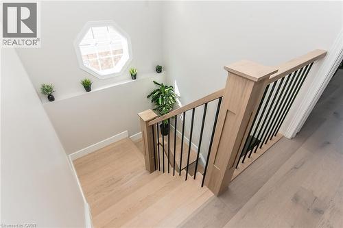 Hardwood staircase with light wood-finish treads and risers, complemented by a contemporary wood newel post and wrought iron balusters - 529 Chesapeake Crescent, Waterloo, ON - Indoor Photo Showing Other Room