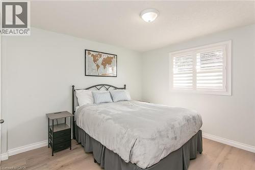 Bedroom featuring light wood-finish flooring, white baseboards, and a window with white louvered shutters - 529 Chesapeake Crescent, Waterloo, ON - Indoor Photo Showing Bedroom