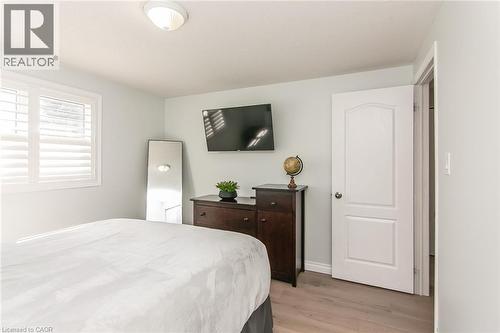 Bedroom featuring wood-finish flooring, a white paneled door, and a window with plantation shutters - 529 Chesapeake Crescent, Waterloo, ON - Indoor Photo Showing Bedroom
