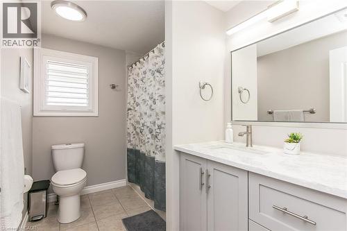 Bathroom featuring a light gray vanity with a single basin, a polished chrome faucet, a large mirror, and a window with white louvered shutters - 529 Chesapeake Crescent, Waterloo, ON - Indoor Photo Showing Bathroom