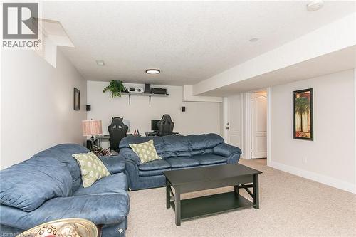 Finished lower level featuring carpet flooring, painted walls, an egress window, and a white interior door - 529 Chesapeake Crescent, Waterloo, ON - Indoor Photo Showing Living Room
