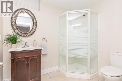 Bathroom featuring a corner shower enclosure with frosted glass, a dark wood vanity with a white countertop, and a decorative oval mirror - 529 Chesapeake Crescent, Waterloo, ON - Indoor Photo Showing Bathroom