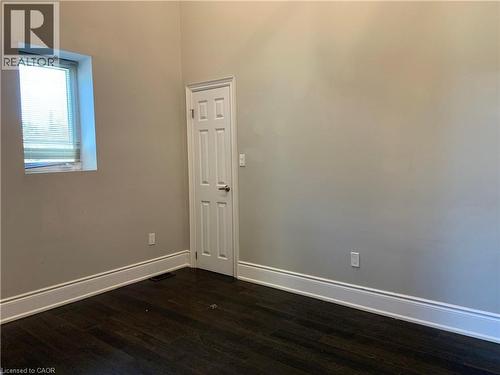 Unit 1 bedroom #2. High ceilings enhancing the sense of space, dark wood-finish flooring, and crisp white baseboards - 405 Macnab Street N, Hamilton, ON 