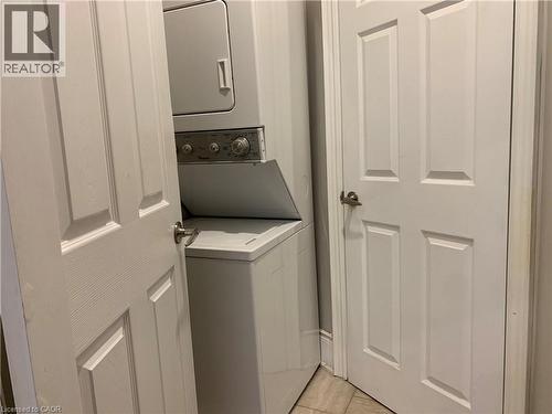 Compact laundry area featuring a white stacked washer and dryer unit - 405 Macnab Street N, Hamilton, ON 