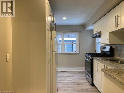 Unit 2 Kitchen featuring white cabinetry, light-toned countertops, a stainless steel gas range, and wood-finish flooring - 405 Macnab Street N, Hamilton, ON 
