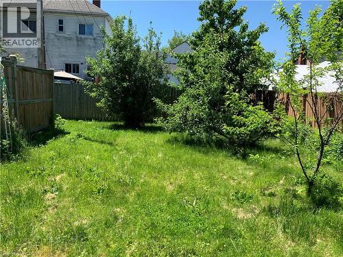 Expansive green lawn area featuring mature trees and partial privacy fencing - 405 Macnab Street N, Hamilton, ON 