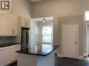 Unit 1 Kitchen featuring vaulted ceilings, white cabinetry with brushed nickel hardware, a black countertop island, stainless steel refrigerator, and dark wood-finish flooring - 405 Macnab Street N, Hamilton, ON 