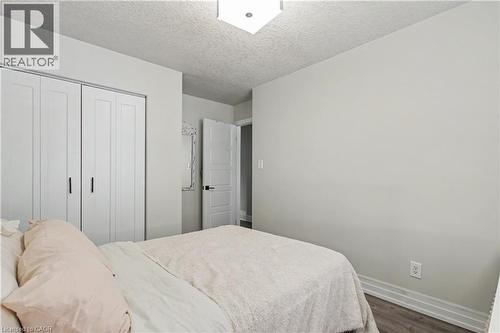 Bedroom featuring white bi-fold closet doors, contemporary light fixture, and wood-finish flooring - 44 Oakhurst Crescent, Kitchener, ON - Indoor Photo Showing Bedroom
