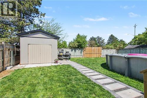 Expansive rear yard featuring a rectangular paver walkway, mature perimeter fencing, and a detached storage shed with a gable roof - 44 Oakhurst Crescent, Kitchener, ON - Outdoor With Backyard