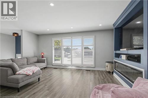 Spacious living area featuring wood-finish flooring, recessed lighting, and a prominent built-in media center with an integrated linear fireplace - 44 Oakhurst Crescent, Kitchener, ON - Indoor Photo Showing Living Room With Fireplace