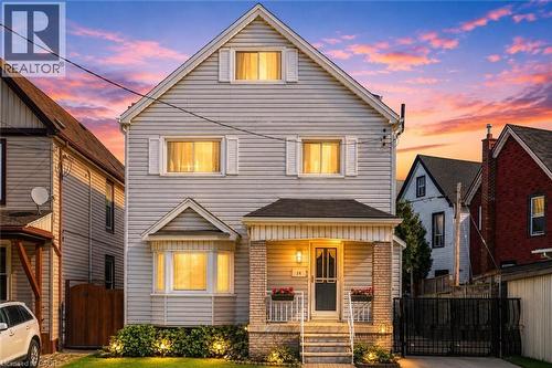 Two-story residence featuring light-colored horizontal siding and a prominent gabled roofline - 14 Niagara Street, Hamilton, ON 